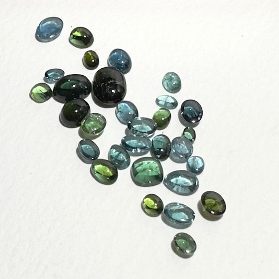 This parcel of 30 pieces of natural unheated tourmaline ranges from light teal blue to mid green to dark teal. They are all eye clean and assorted size cabochon cut.