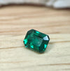 Faceted green gemstone on a wooden surface