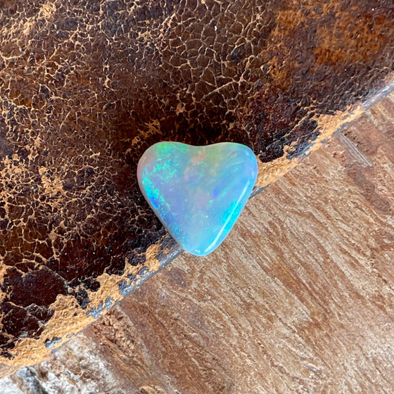 2.05 heart shaped crystal opal, this small bright heart has bright flashes of green, there is a darker line on one side.