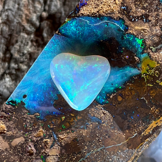 2.05 heart shaped crystal opal, this small bright heart has bright flashes of green, there is a darker line on one side.