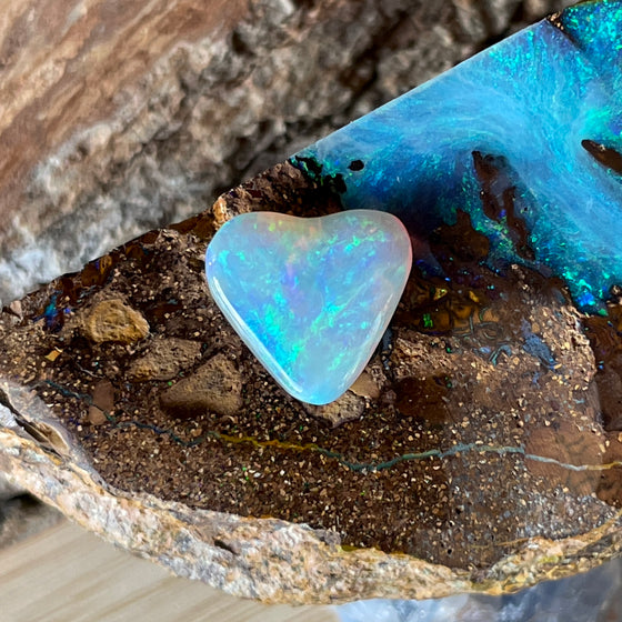 2.05 heart shaped crystal opal, this small bright heart has bright flashes of green, there is a darker line on one side.
