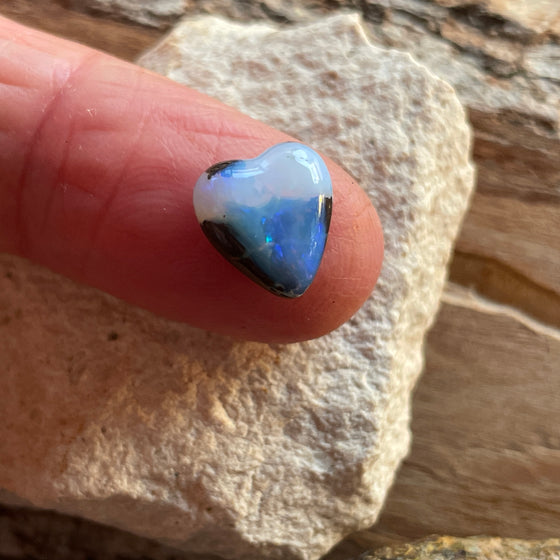 5ct Heart Shape Boulder Opal, this tiny heart is clear misty blue across the top with a slightly darker blue at the base. The cutter has used the patterns in the opal to enhance the piece.