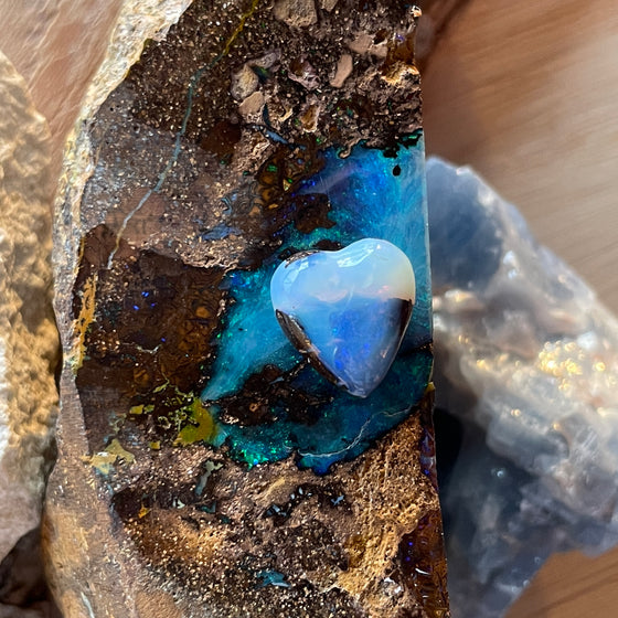 5ct Heart Shape Boulder Opal, this tiny heart is clear misty blue across the top with a slightly darker blue at the base. The cutter has used the patterns in the opal to enhance the piece.