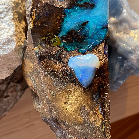 5ct Heart Shape Boulder Opal, this tiny heart is clear misty blue across the top with a slightly darker blue at the base. The cutter has used the patterns in the opal to enhance the piece.